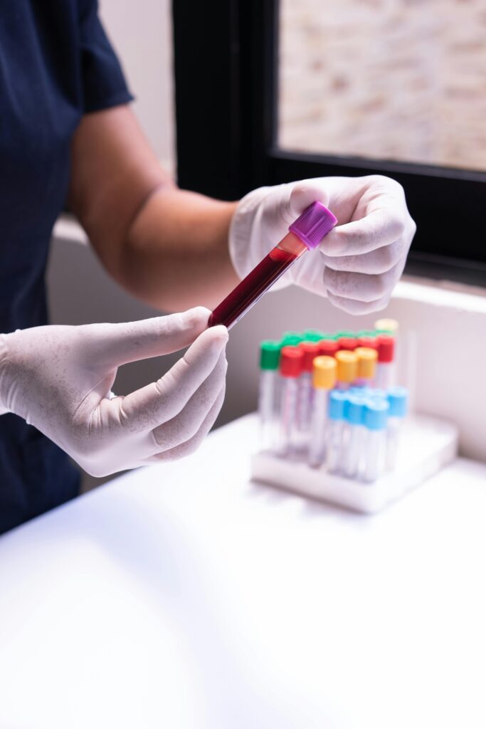 A healthcare worker examines a blood sample in test tubes, emphasizing medical precision and care.